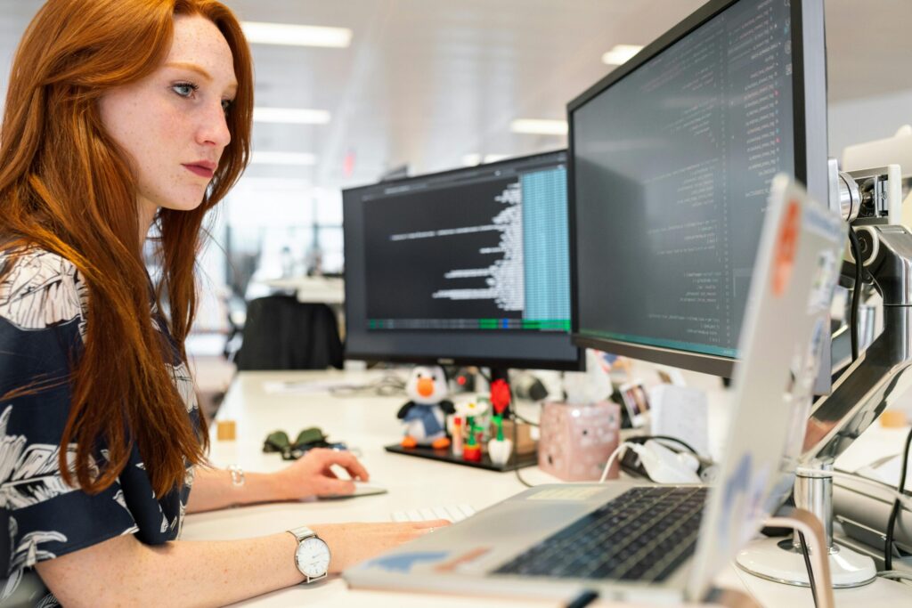 pexels-photo-3861958-3861958 A focused female software engineer coding on dual monitors in a modern office.